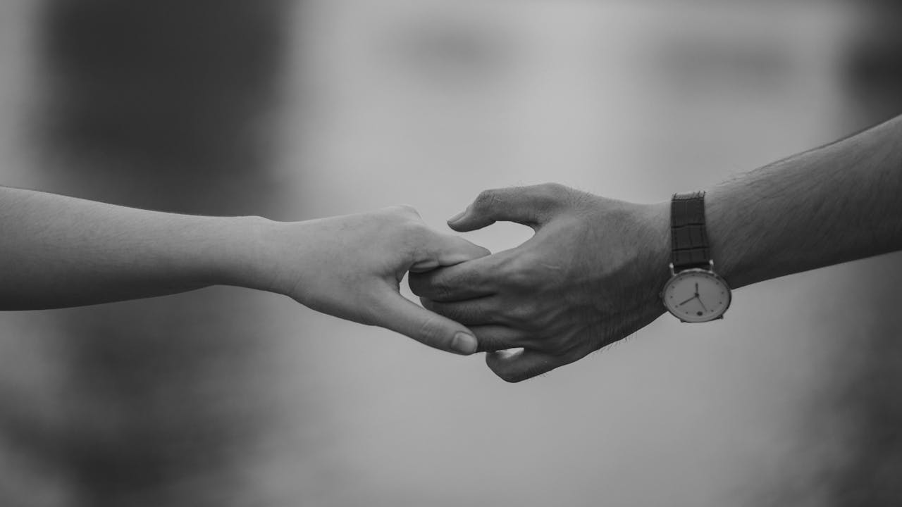 our-story Monochrome image of two hands holding, symbolizing love and connection.