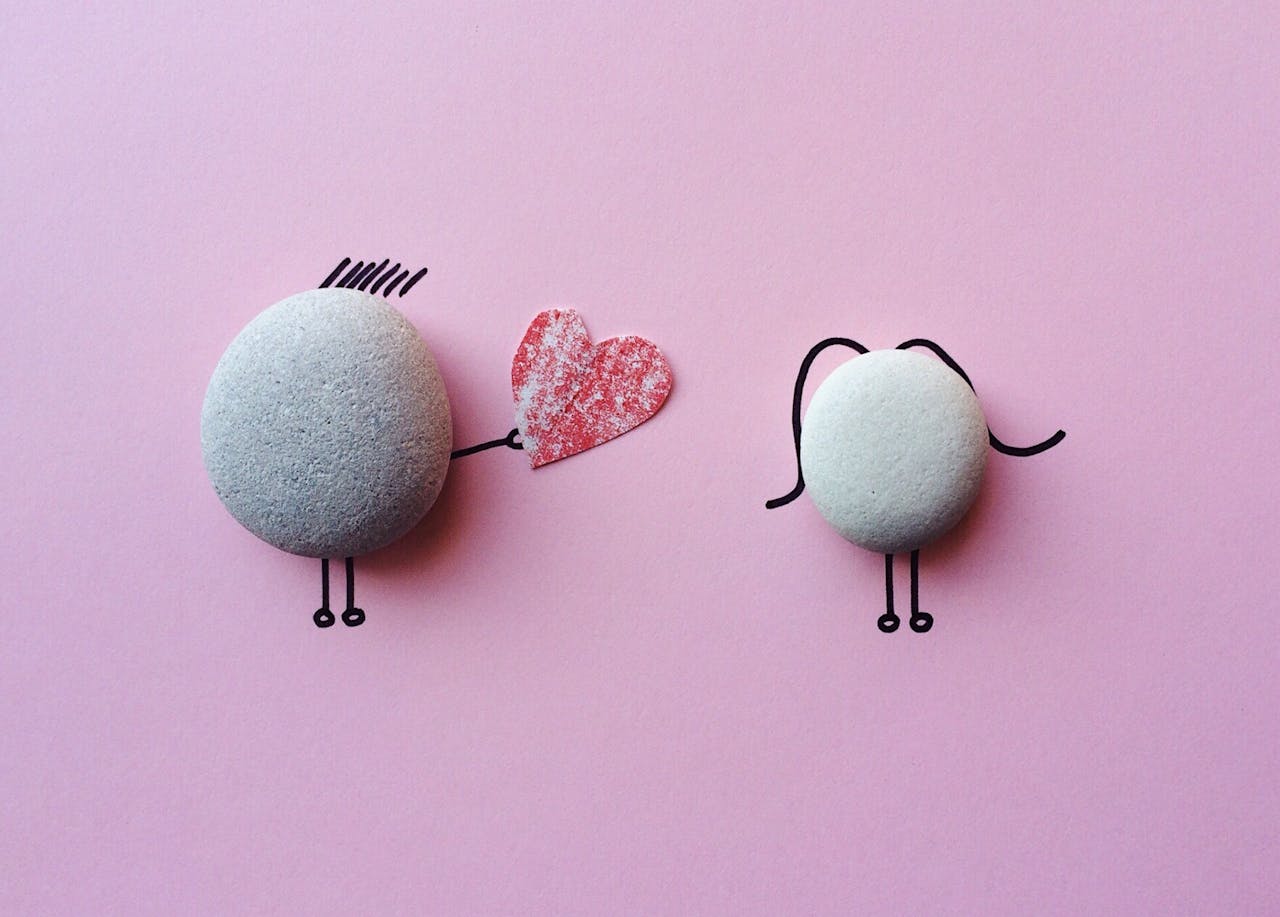 about-us Charming stone art with heart symbol on pink background, symbolizing love and connection.